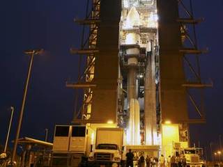 The Atlas V rocket set to launch NASA's Mars Science Laboratory (MSL) mission is illuminated inside the Vertical Integration Facility at Space Launch Complex 41, where employees have gathered to hoist the spacecraft's multi-mission radioisotope thermoelectric generator (MMRTG).
