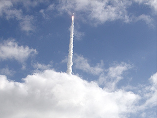 With NASA's Mars Science Laboratory (MSL) spacecraft sealed inside its payload fairing, the United Launch Alliance Atlas V rocket rides a tall pillar of smoke and flames as it soars over Space Launch Complex-41 on Cape Canaveral Air Force Station in Florida, after liftoff at 10:02 a.m. EST Nov. 26.
