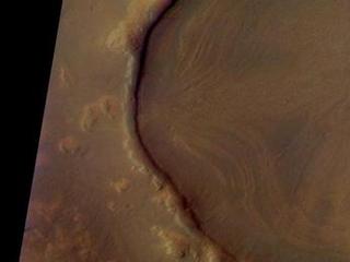This is a Mars Odyssey visible color image of an unnamed crater in western Arcadia Planitia (near 39 degrees N, 179 degrees E). The crater shows a number of interesting internal and external features that suggest that it has undergone substantial modification since it formed. These features include concentric layers and radial streaks of brighter, redder materials inside the crater, and a heavily degraded rim and ejecta blanket. The patterns inside the crater suggest that material has flowed or slumped towards the center. Other craters with features like this have been seen at both northern and southern mid latitudes The distribution of these kinds of craters suggests the possible influence of surface or subsurface ice in the formation of these enigmatic features. The image was taken on September 29, 2002 during late northern spring. This is an approximate true color image, generated from a long strip of visible red (654 nm), green (540 nm), and blue (425 nm) filter images that were calibrated using a combination of pre-flight measurements and Hubble images of Mars. The colors appear perhaps a bit darker than one might expect; this is most likely because the images were acquired in late afternoon (roughly 4:40 p.m. local solar time) and the low Sun angle results in an overall darker surface.