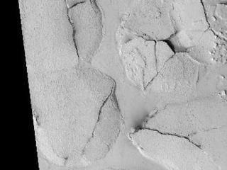 This HiRISE image (PSP_003597_1765), shows fractured mounds on the southern edge of Elysium Planitia.

The mounds are typically a few kilometers in diameter and about 200 feet tall. The fractures that crisscross their surfaces are dilational (extensional) in nature, suggesting that the mounds formed by localized uplift (i.e., they were pushed up from below).

The mounds are probably composed of solidified lava. They are contiguous with, and texturally similar to, the flood lavas that blanket much of Elysium Planitia, and, where dilation cracks provide cross-sectional exposure, the uplifted material is rocky.

Patches of mechanically weak and disrupted material overlie the rocky mound material. This is particularly conspicuous in the northeast corner of the HiRISE image. These patches may be remnants of a layer that was once more continuous but has been extensively eroded. Smooth lava plains fill the low-lying areas between the mounds. They are riddled with sinuous pressure ridges. The entire area is covered by a relatively thin layer of dust and sand.