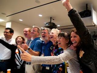 Members of the Curiosity science team jump out of their seats and cheer when they hear that the Curiosity rover has successfully landed on the Martian surface.