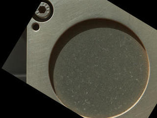 A sample of basaltic rock from a lava flow in New Mexico serves as a calibration target carried on the front of NASA's Mars rover Curiosity for the rover's Canadian-made Alpha Particle X-Ray Spectrometer (APXS) instrument.