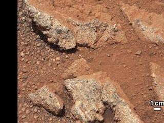 In this image from NASA's Curiosity rover, a rock outcrop called Link pops out from a Martian surface that is elsewhere blanketed by reddish-brown dust. The fractured Link outcrop has blocks of exposed, clean surfaces.