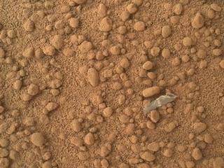 This image from the Mars Hand Lens Imager (MAHLI) camera on NASA's Mars rover Curiosity shows a small bright object on the ground beside the rover at the "Rocknest" site.