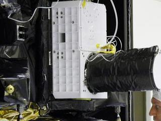 With the Compact Reconnaissance Imaging Spectrometer for Mars (CRISM) instrument just above his head, a technician at NASA's Kennedy Space Center works on the Mars Reconnaissance Orbiter spacecraft in July 2005.