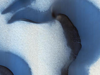 This picture was taken during the Martian summer with only small patches of ice remaining at the surface; they show up as bright, somewhat blue, spots on slopes that provide some shading from the Sun.