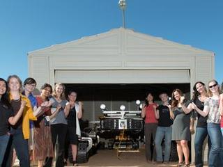 This is a picture of some of the women working on the Curiosity rover posing with Curiosity's mobility double, "Scarecrow," used to test drive under different soil conditions in the JPL "Mars Yard."