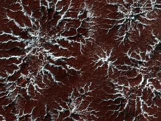On Mars the seasonal polar caps are composed of dry ice (carbon dioxide). In the springtime as the sun shines on the ice, it turns from solid to gas and causes erosion of the surface