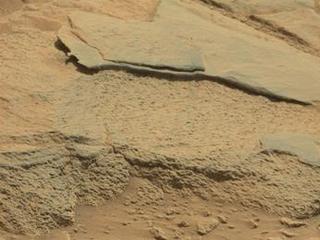 The rock "Ithaca" shown here, with a rougher lower texture and smoother texture on top, appears to be a piece of the local sedimentary bedrock protruding from the surrounding soil in Gale Crater.