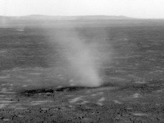 This image hows several dust devils moving from right to left across a plain inside Mars' Gusev Crater, as seen from the vantage point of NASA's Mars Exploration Rover Spirit in hills rising from the plain.