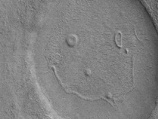 This picture of a crater resembling a "happy face" was taken in January 2008, by the Mars Reconnaissance Orbiter's Context Camera. The unnamed crater is almost 2 miles (about 3 kilometers) across.