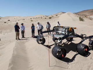sand dune, mars rover, wheel, Dumont, Scarecrow, test - Several engineers watch as the Scarecrow test rover goes over a dunes obstacle course.