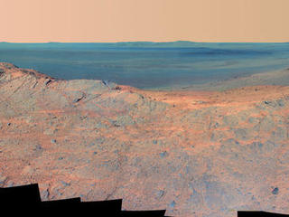 This May 14, 2014, scene from the Pancam on NASA's Mars Exploration Rover Opportunity catches "Pillinger Point," on the western rim of Endeavour Crater, in the foreground and the crater's eastern rim on the horizon. The scene's false color makes differences in surface materials more easily visible.