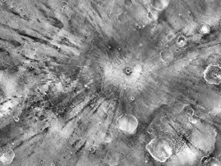 A small impact crater on Mars named Gratteri, 4.3 miles (6.9 km) wide, lies at the center of large dark streaks.