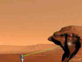 This picture shows a flat, rock-strewn surface with cliffs in the distance and a six-wheeled robotic vehicle in the foreground. A short distance to the right of the vehicle is a layered cliff. An instrument attached to the mast of the vehicle is shooting a beam of light at the surface of the cliff.