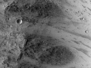 A path resembling a dotted line from the upper left to middle right of this image is the track left by an irregularly shaped, oblong boulder as it tumbled down a slope on Mars before coming to rest in an upright attitude at the downhill end of the track.