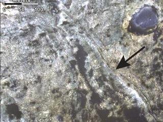 This image shows distinct bands of alternating tone and brightness within the "Murray Formation" on Mars. A black arrow  points to those bands, which cut across diagonally in this image.
