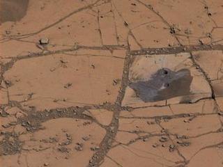 This image shows the first holes drilled by NASA's Mars rover Curiosity at Mount Sharp. The loose material near the drill holes is drill tailings and an accumulation of dust that slid down the rock during drilling.