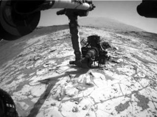 This view from the wide-angle Hazard Avoidance Camera on the front of NASA's Curiosity Mars Rover shows the rover's drill in position for a mini-drill test to assess whether a rock target called "Mojave" is appropriate for full-depth drilling to collect a sample.  It was taken on Jan. 13, 2015.