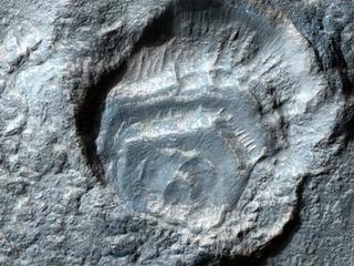 This image features a gray crater in the middle with a deep hole that looks like it was struck multiple times by a Martian meteorite.