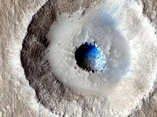 This is an image of a small, gray impact crater with a bowl-shaped rim.