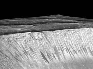 Dark narrow streaks, called "recurring slope lineae," emanate from the walls of Garni Crater on Mars, in this view constructed from observations by the High Resolution Imaging Science Experiment (HiRISE) camera on NASA's Mars Reconnaissance Orbiter.