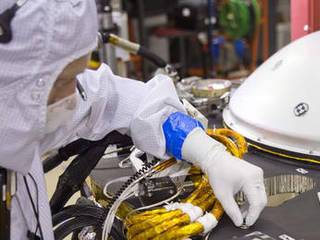 A spacecraft specialist in a clean room at Lockheed Martin Space Systems in Denver, where the InSight lander is being built, affixes a dime-size chip onto the lander deck in November 2015.
