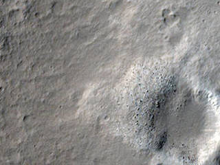 This area of Mars has a few gray craters, with white/light material surrounding it.