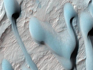 This scene shows dark sand dunes marching over the ridges created by an alluvial (water-deposited) fan in an impact crater.