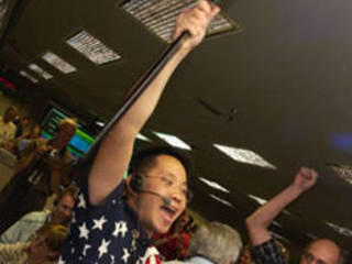 Dr. Wayne Lee, chief engineer for development of the Mars Exploration Rover's descent and landing systems proudly waves a broom, indicating a clean martian sweep.