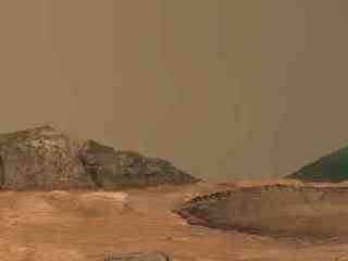 This image shows a round crater exposing horizontal layers in its walls. Around it is an undulating brown surface. In both the foreground, in the lower right corner of the image, and in the backround, forming the horizon, are cliffs exposing horizontal layers of rock. The sky is a typical shade of martian peachy pink.