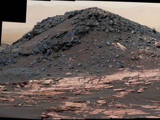 This view from the Curiosity Mars rover's Mastcam shows a dark mound, called "Ireson Hill," which rises about 16 feet above redder layered outcrop material on lower Mount Sharp, Mars, near a location where Curiosity examined a linear sand dune in February 2017.