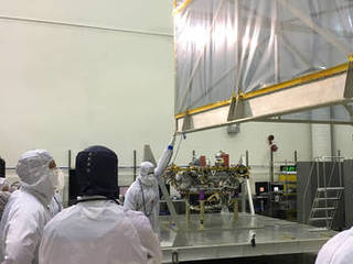 In a Lockheed Martin clean room facility near Denver in June 2017, members of the InSight mission's assembly, test and launch operations team remove the inner layer of protective housing that covered NASA's InSight spacecraft while the spacecraft was in storage after a launch postponement.